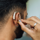 Man adjusting hearing aid